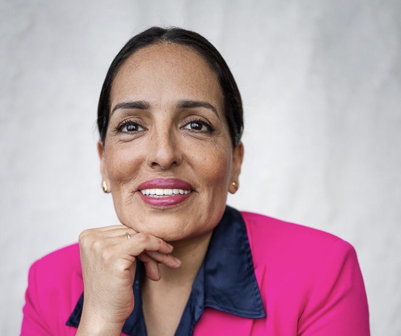 Alma Blue smiling, in a pink blazer